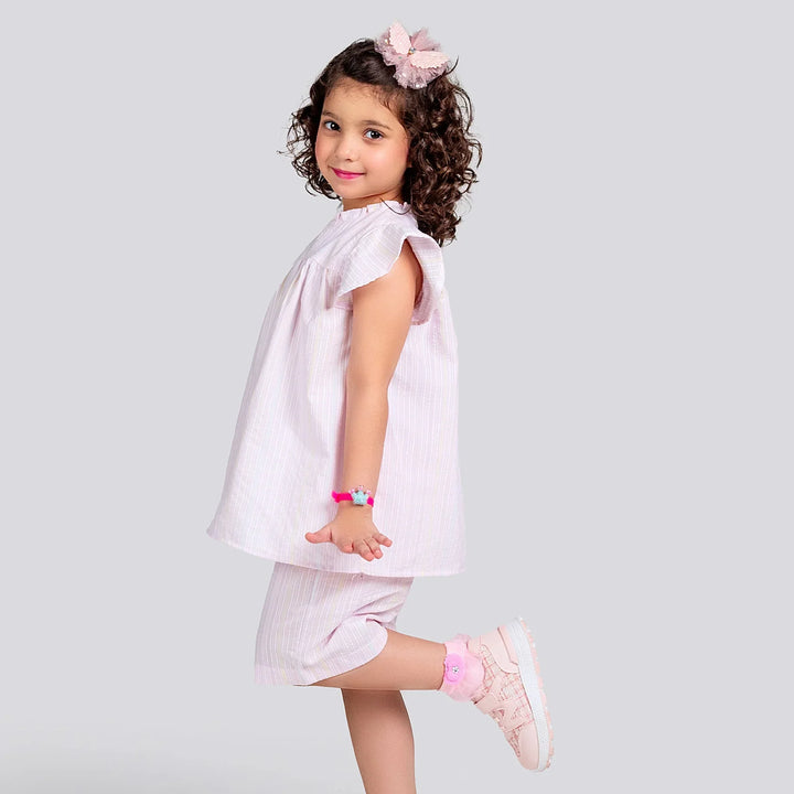 Young girl in a pink dress with matching accessories on a light gray background