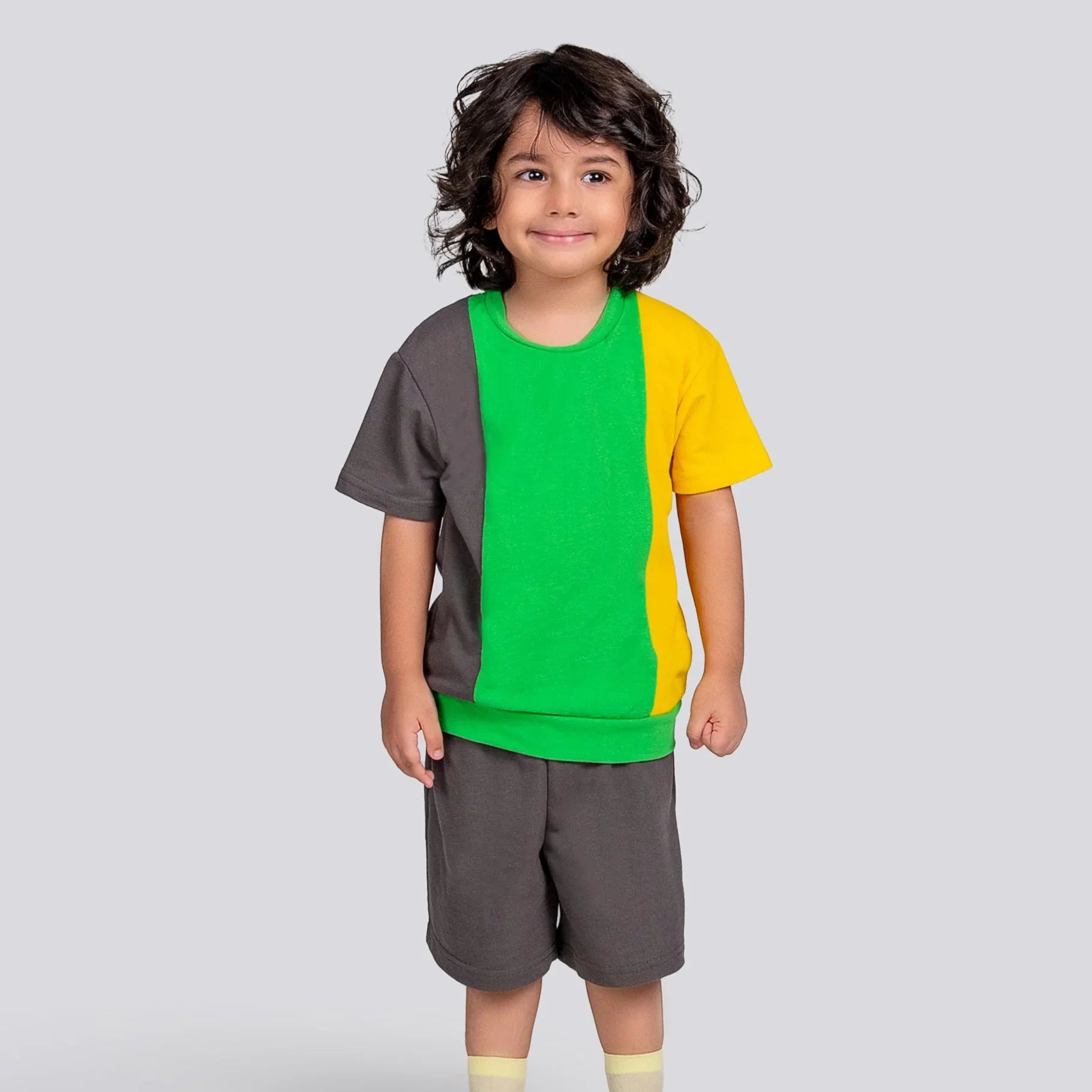 Child wearing a colorful shirt and shorts set on a light gray background