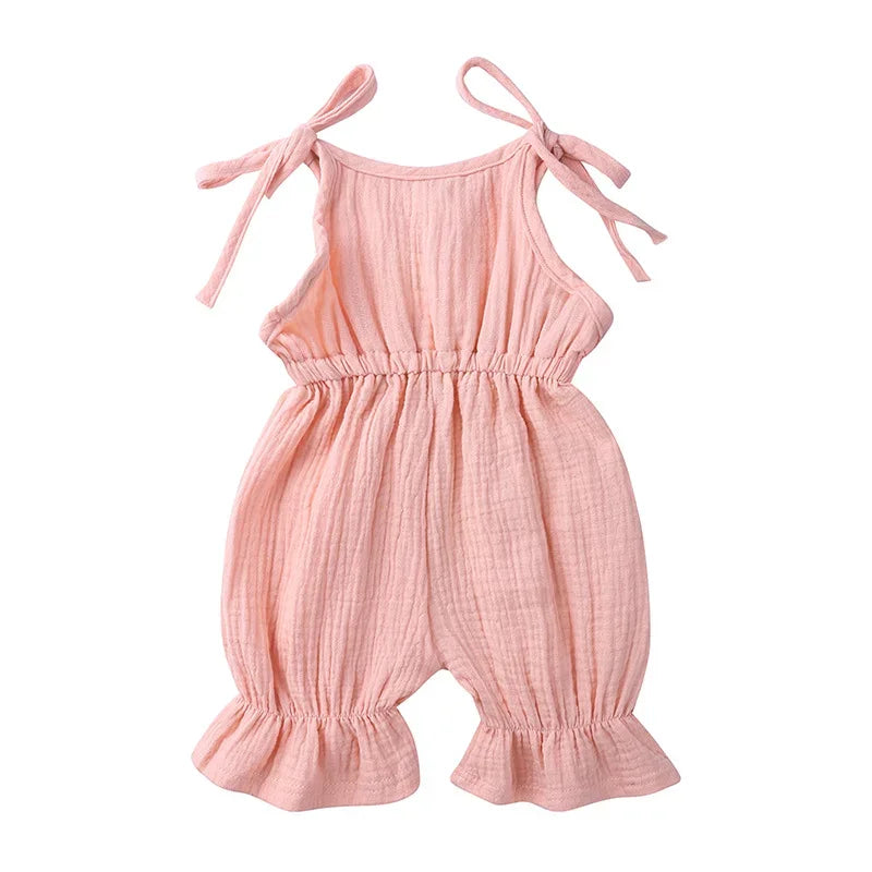Pink baby romper with bow straps on a white background