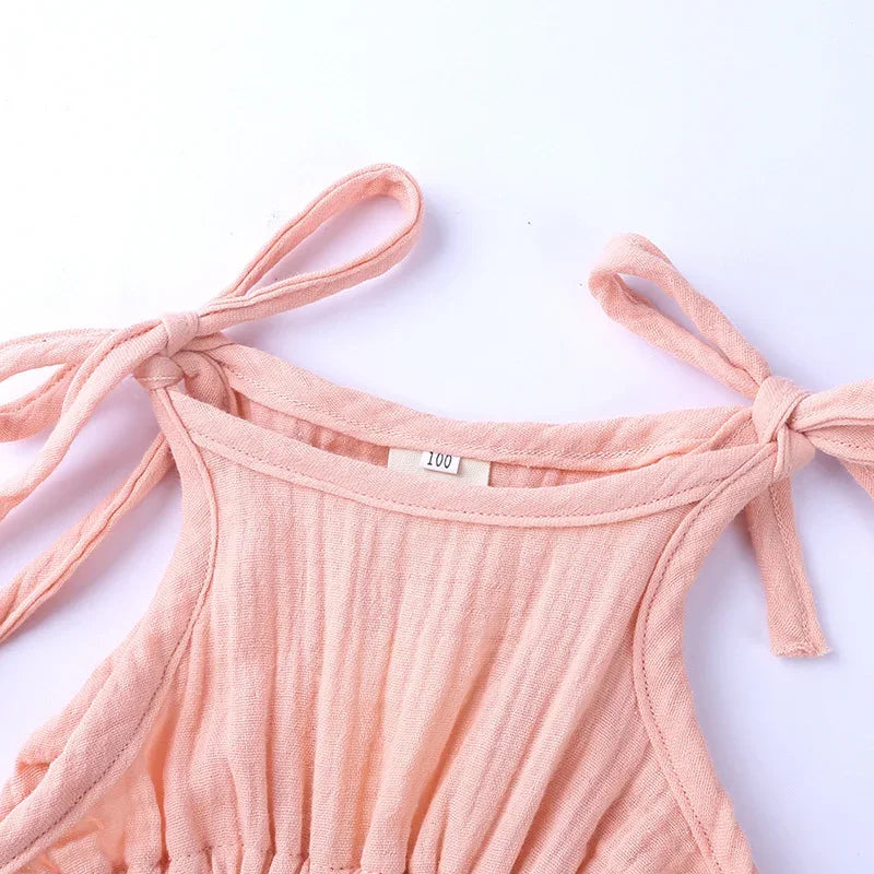 Pink ribbed tank top with tied straps on a white background