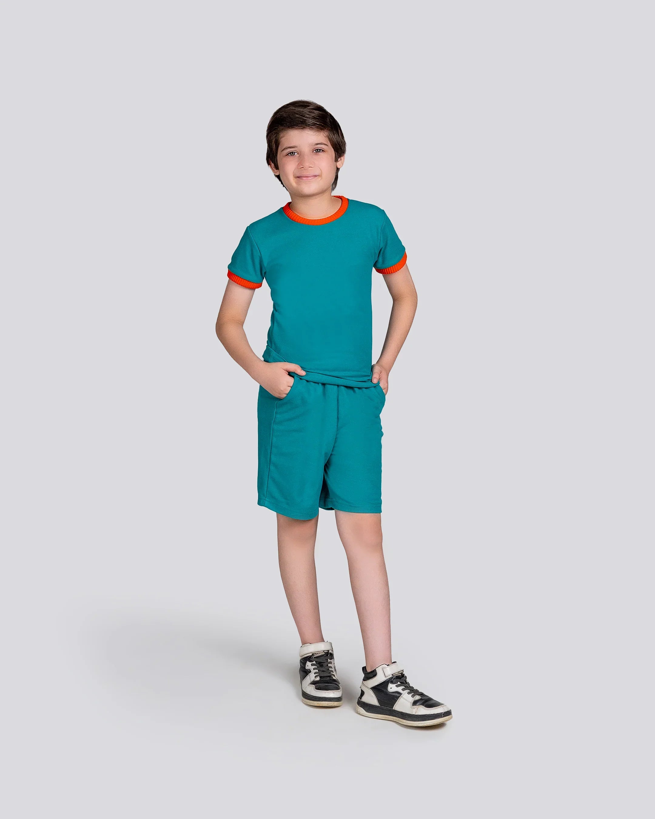 Child wearing a teal outfit with orange accents on a white background