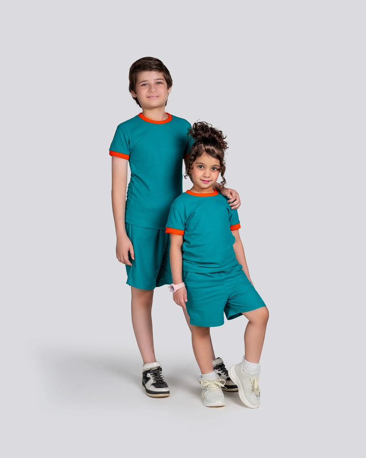 Two children wearing matching teal outfits with orange accents on a light gray background