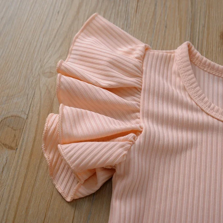Pink ribbed top with ruffled details on a wooden surface