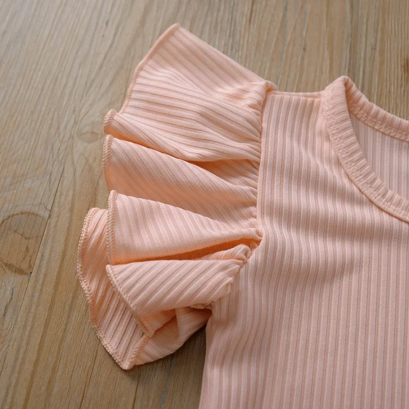 Pink ribbed top with ruffled details on a wooden surface