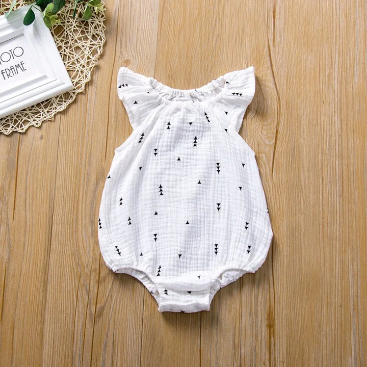 White baby romper with black patterns on a wooden surface