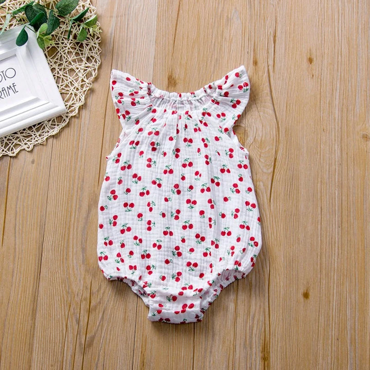 Baby romper with cherry pattern on a wooden surface