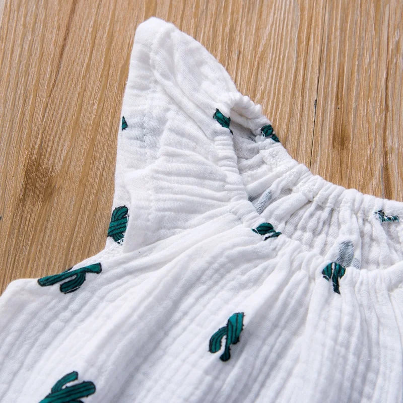 White fabric with green embroidered patterns on a wooden surface