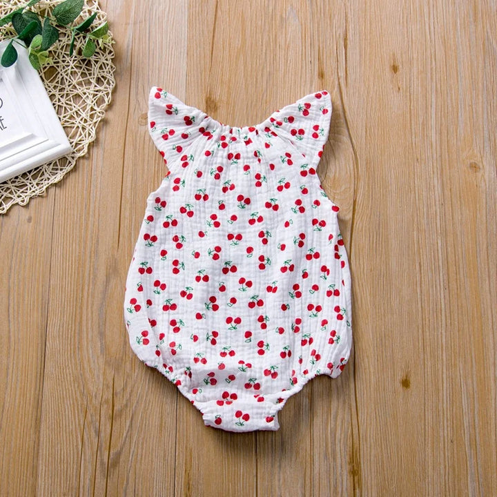 Baby romper with cherry pattern on a wooden surface