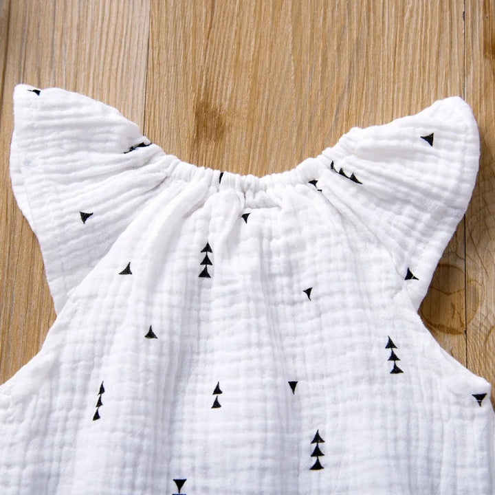 White sleeveless top with black triangle patterns on a wooden surface