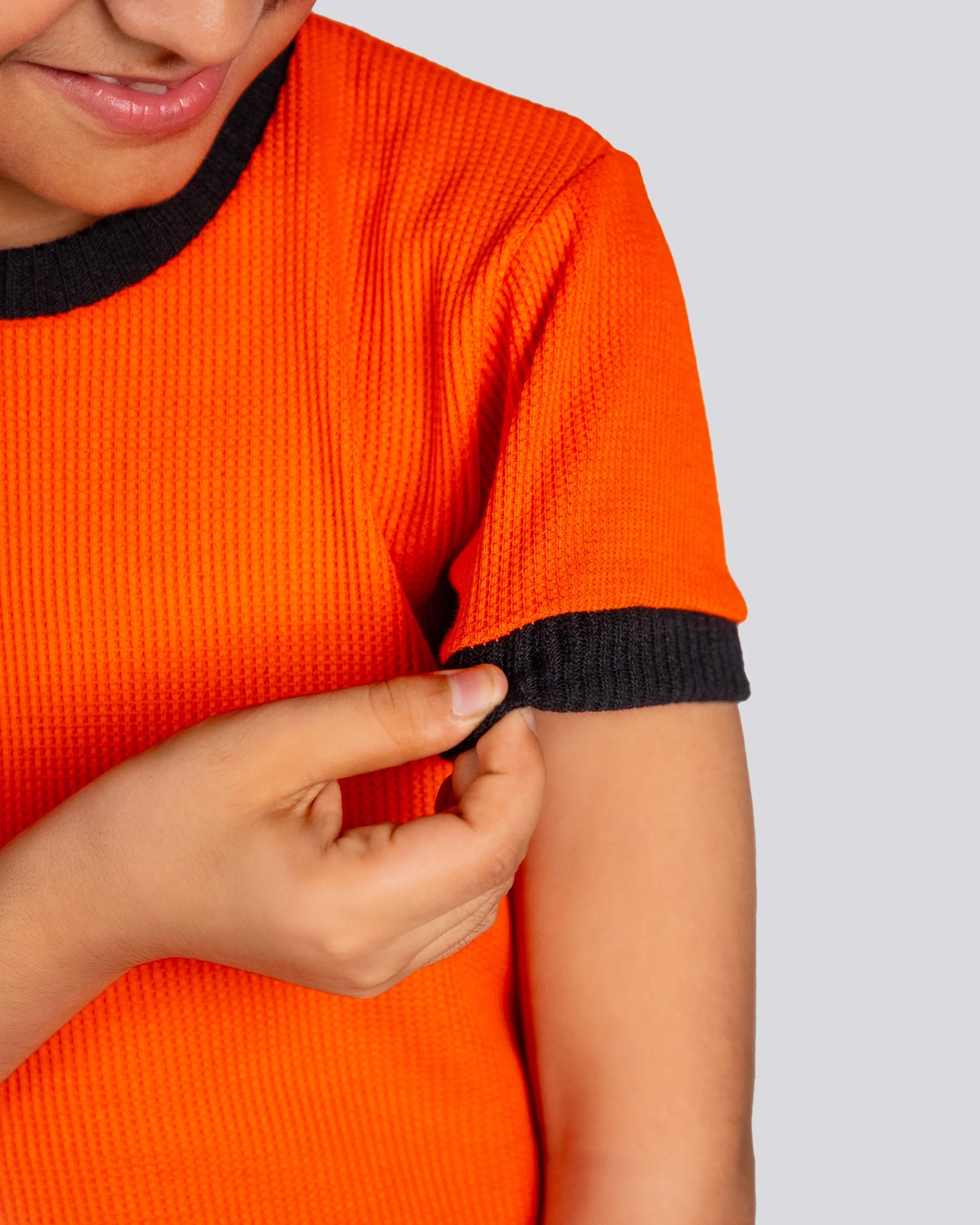 Person wearing an orange shirt with black trim on a plain background