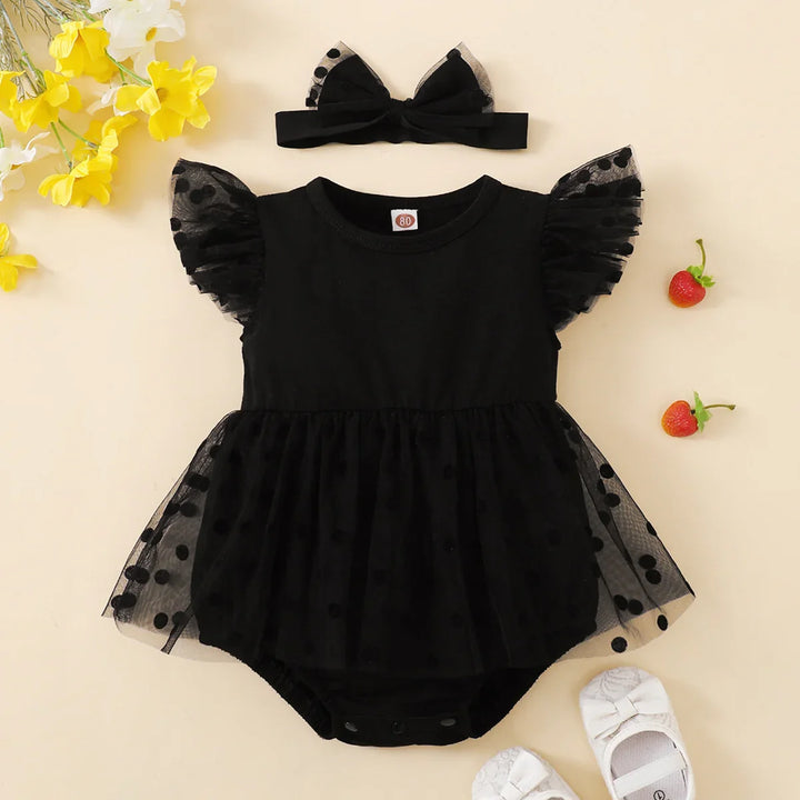 Black baby romper with tulle and a matching headband on a beige background.