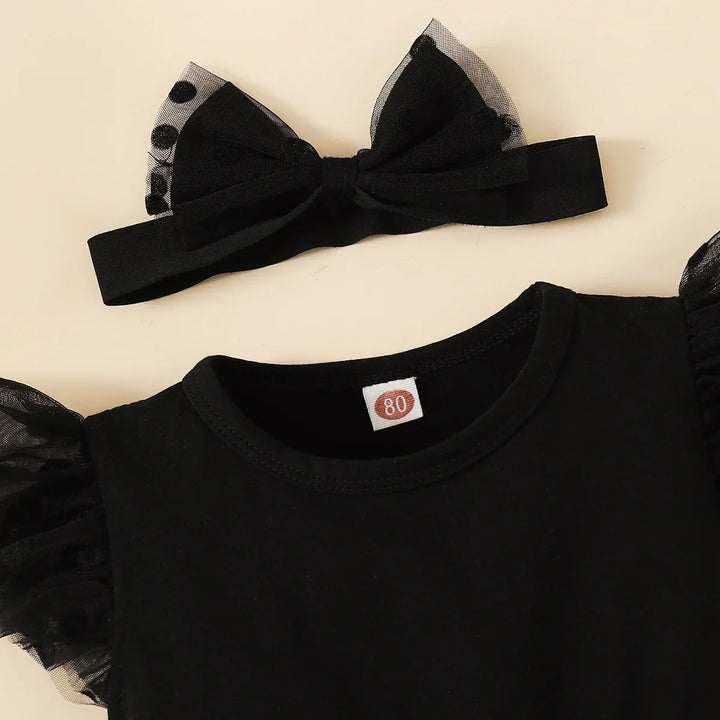 Black outfit with sheer bow and matching headband on a beige background