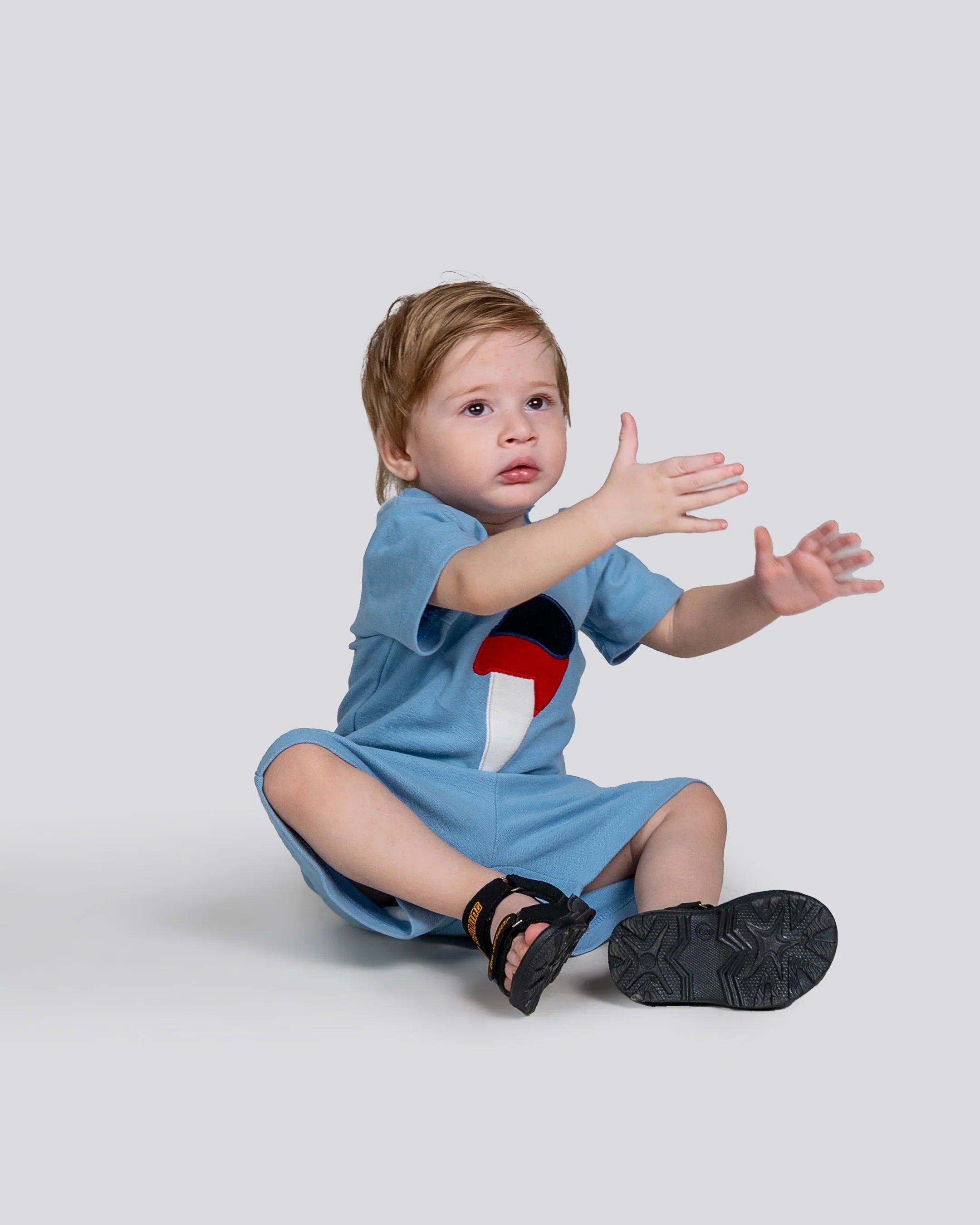 Child wearing a blue dress with a red and black design on a light gray background