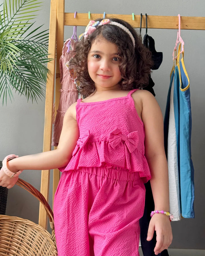 Young girl in a pink outfit standing in front of a rack with clothes.