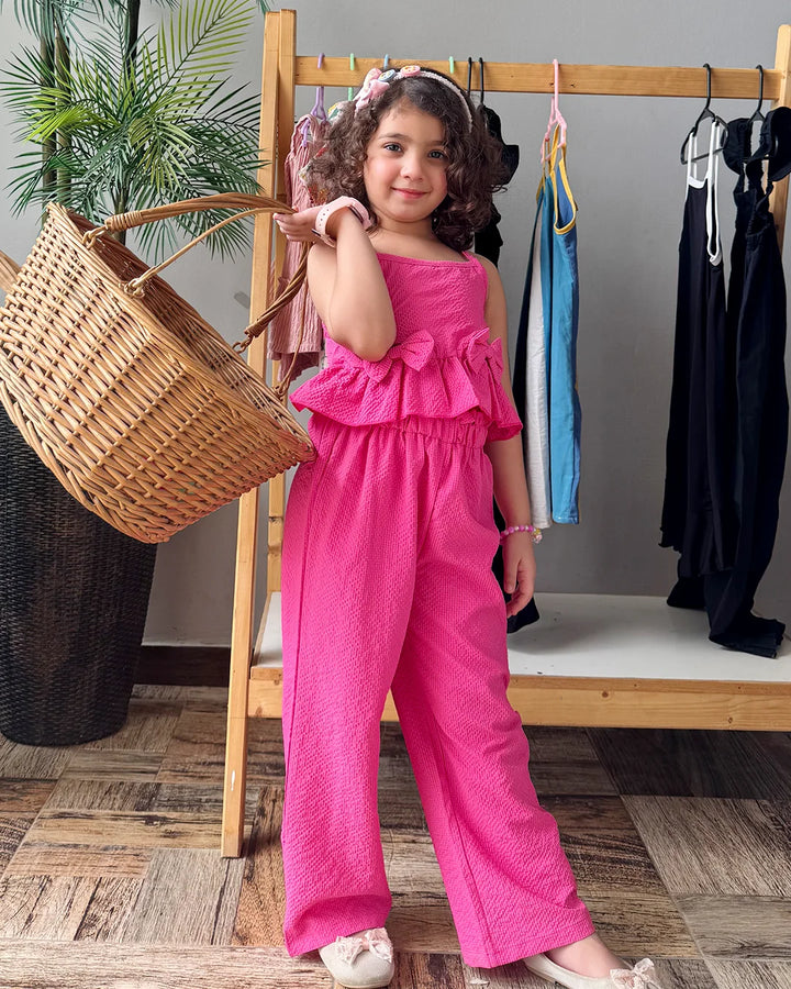 Young girl in a pink outfit standing in a room with clothing racks and a basket.