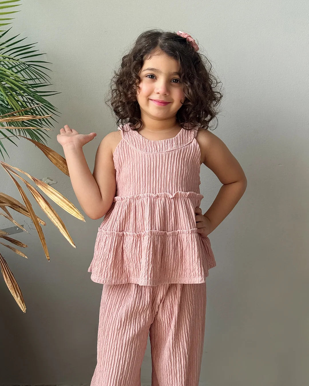 Young girl wearing a pink outfit standing against a plain background