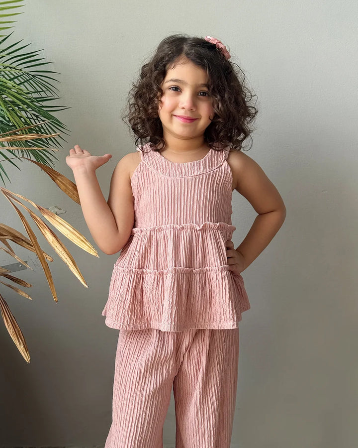 Young girl wearing a pink outfit standing against a plain background