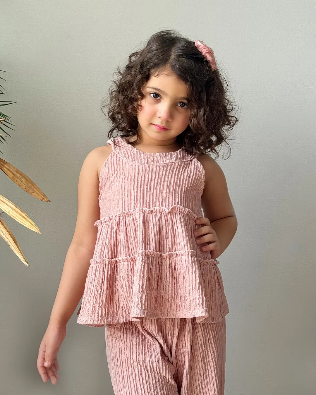 Young girl wearing a pink tiered outfit against a neutral background