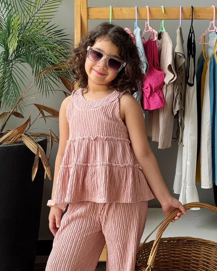 Child in a pink outfit holding a basket, standing in front of a rack of clothes.