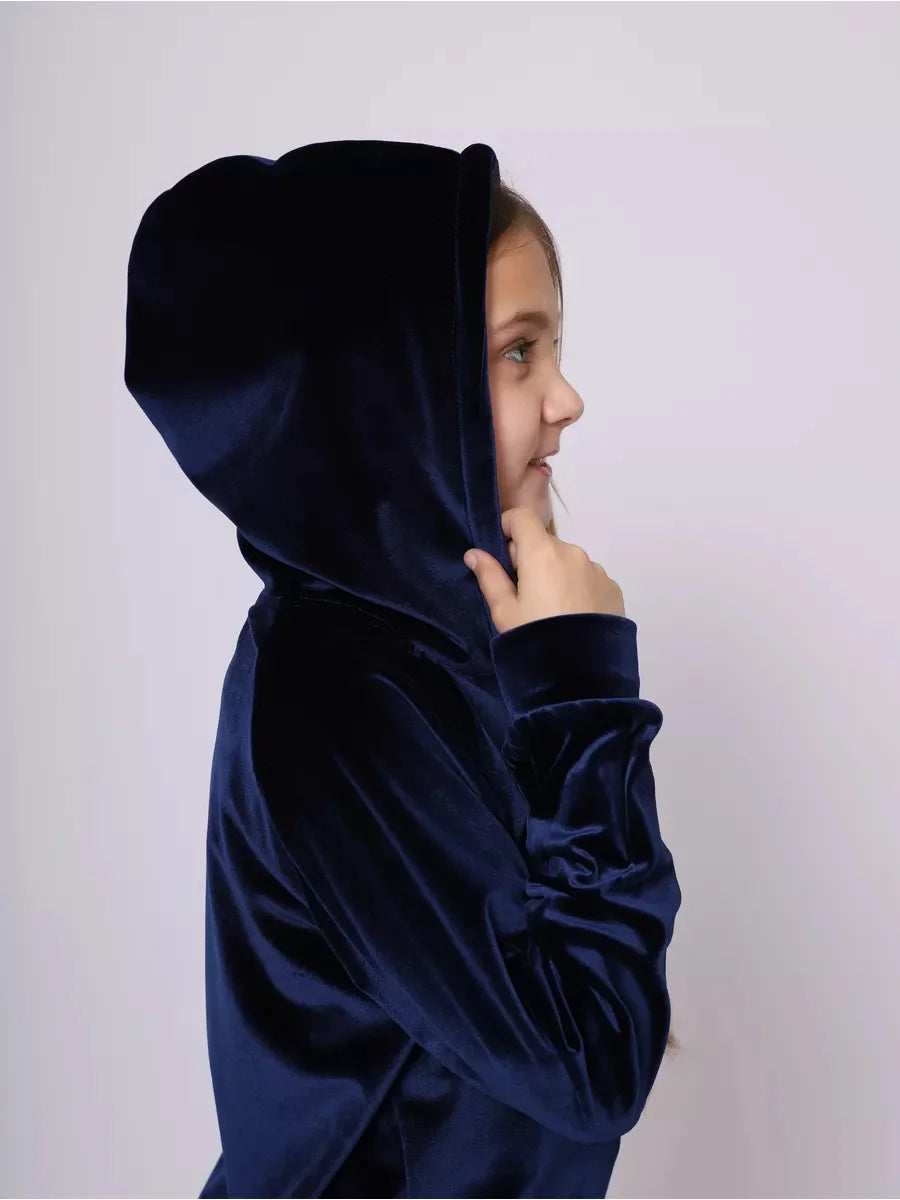 Child wearing a dark blue hooded garment against a plain background