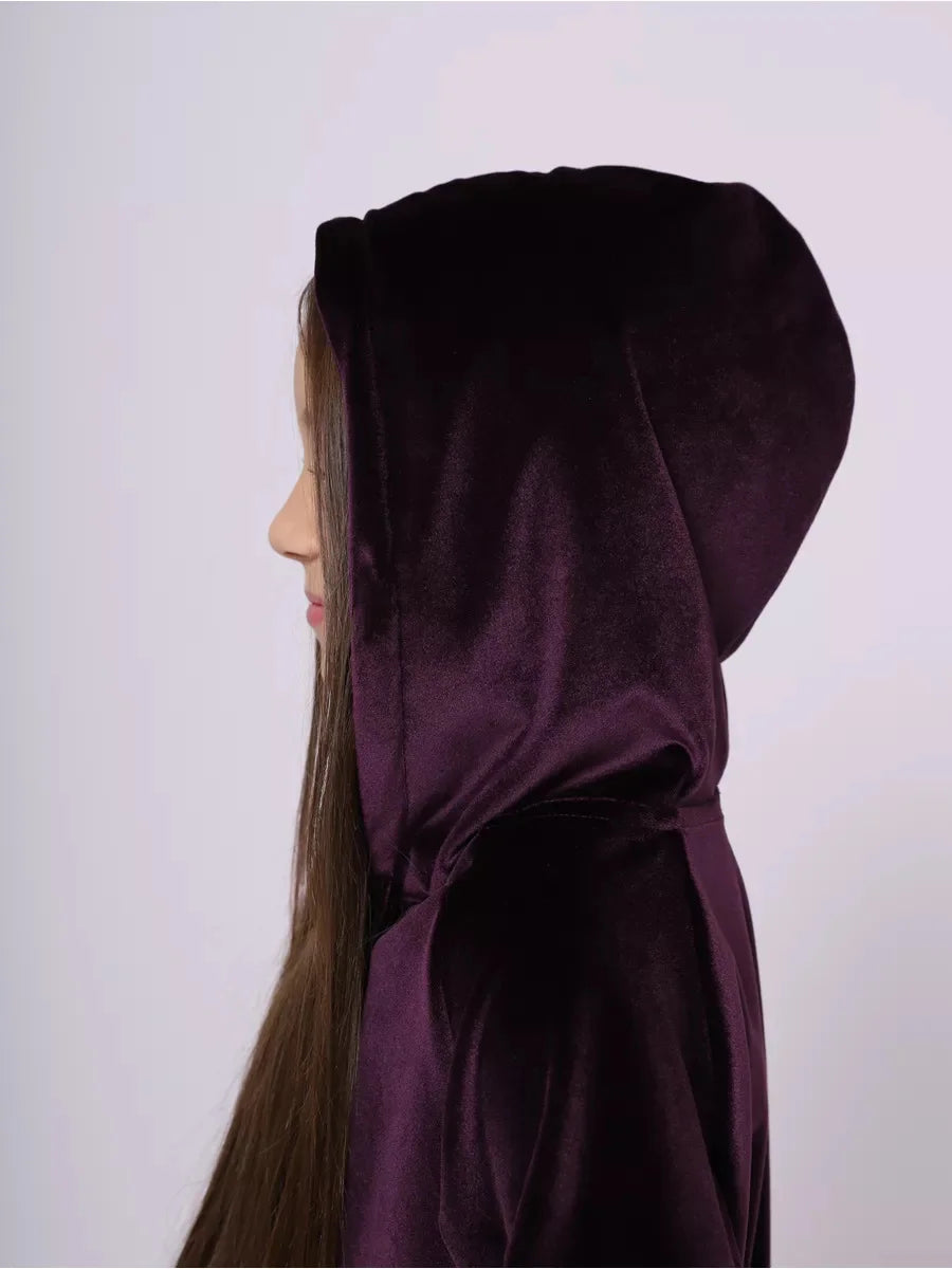 Person wearing a dark purple hooded garment against a plain background