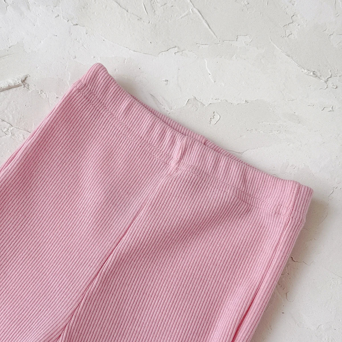 Pink ribbed fabric on a textured white surface
