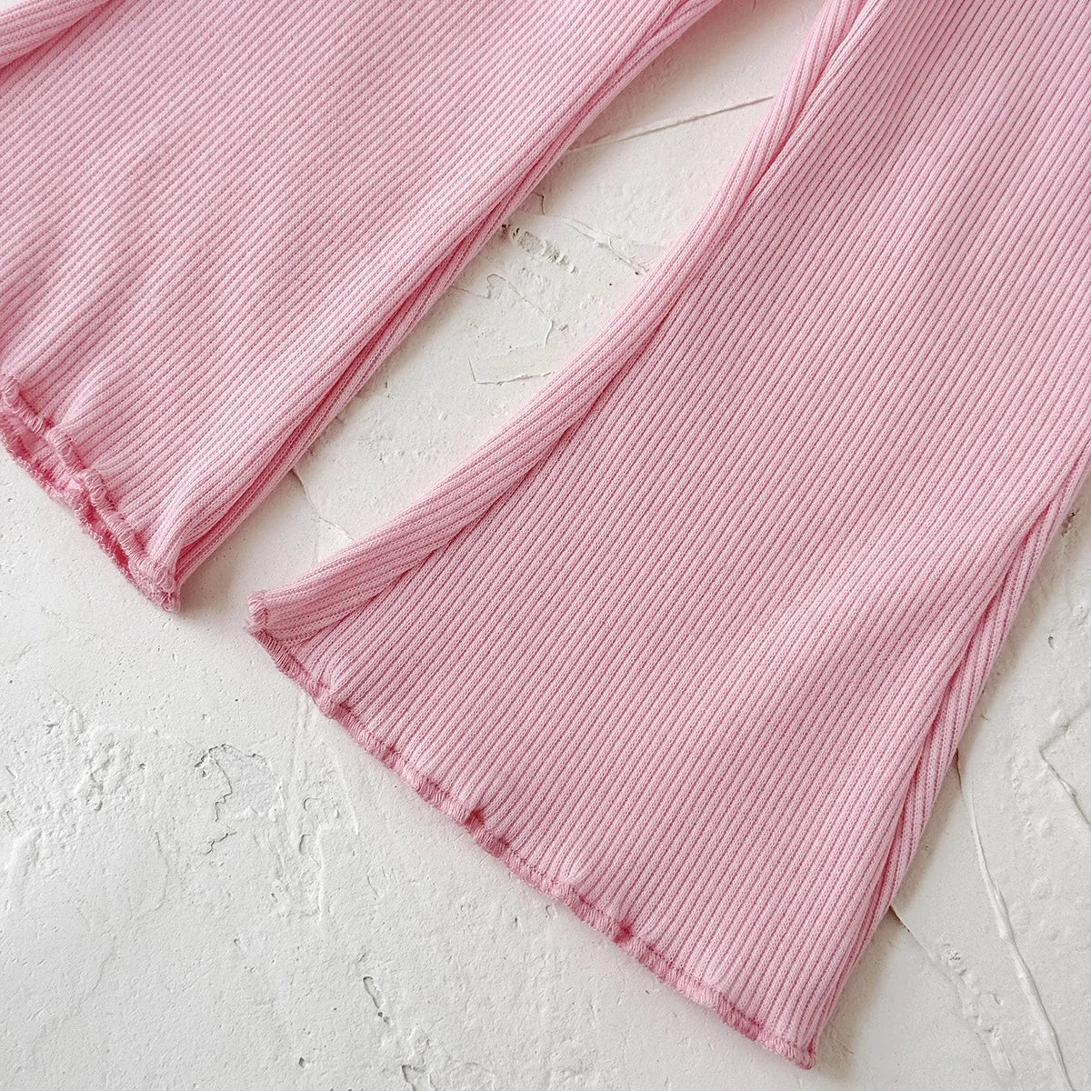 Pink ribbed fabric on a light gray surface
