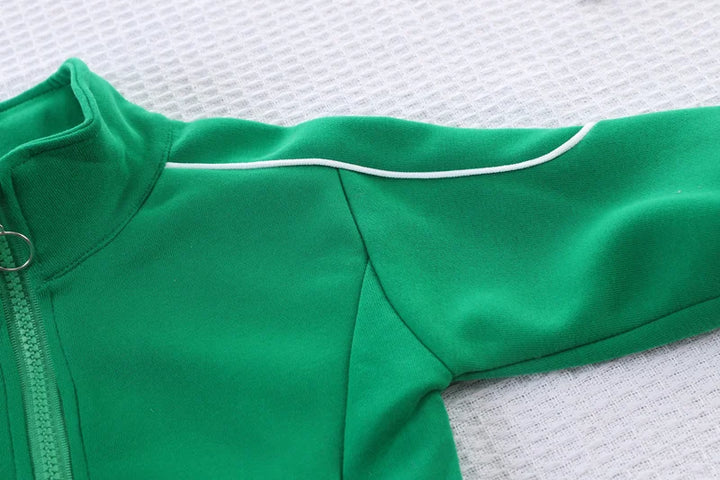 Green baby onesie with white trim on a textured white background