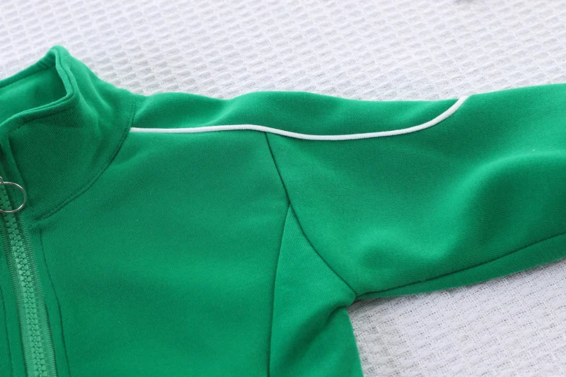 Green baby onesie with white trim on a textured white background