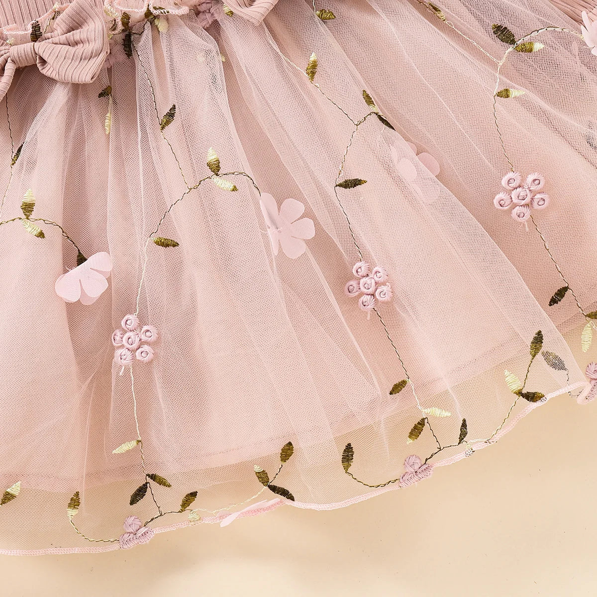 Pink tulle skirt with floral and butterfly embroidery on a beige background