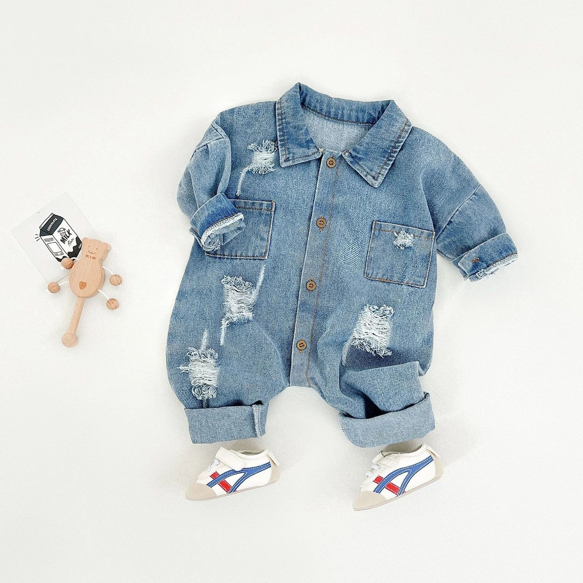 Denim baby outfit with distressed details on a white background