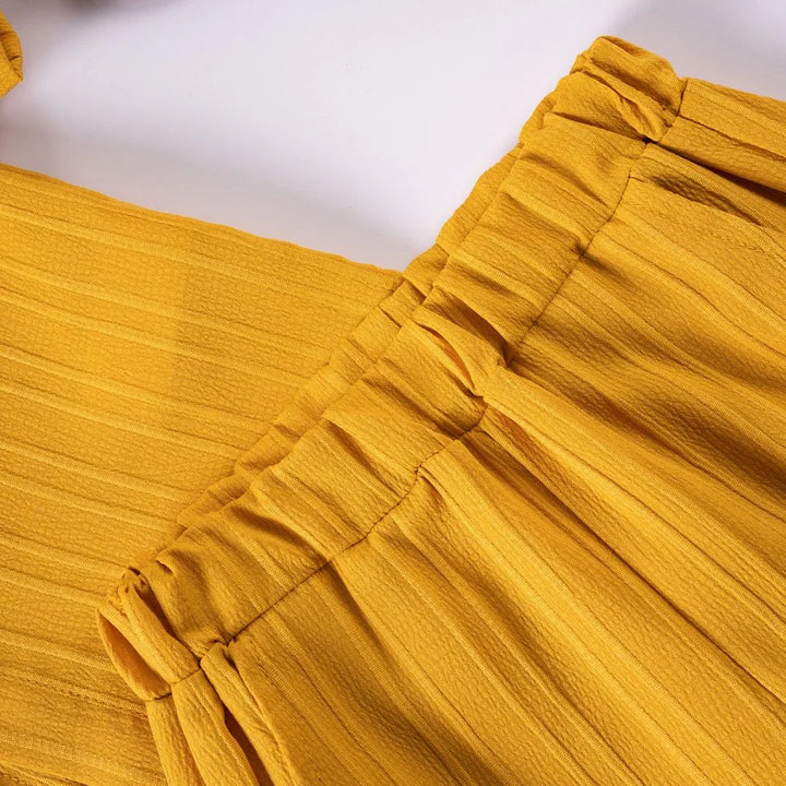 Close-up of a yellow textured fabric with pleated details on a white background