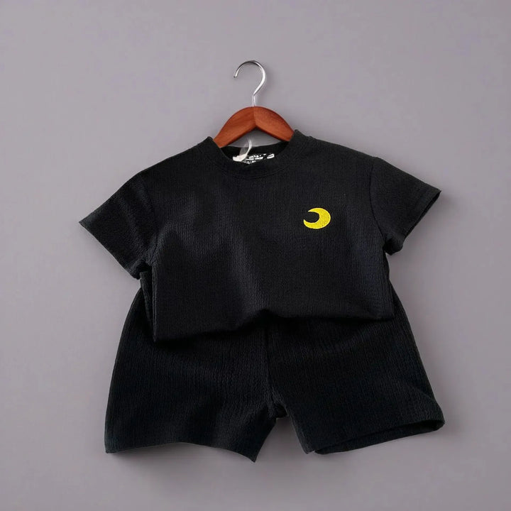 Black children's outfit with yellow moon design on a gray background