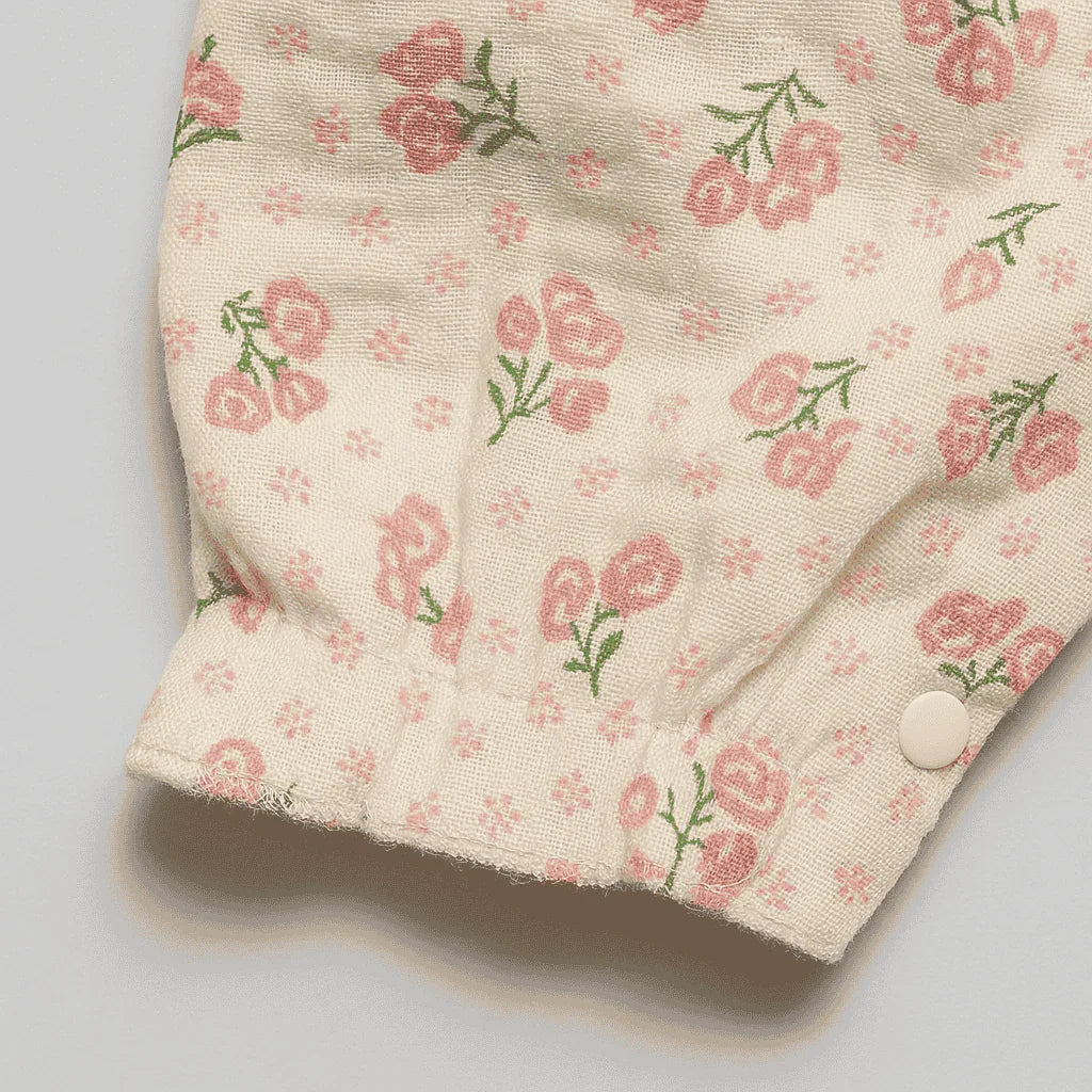 Floral patterned fabric with pink roses and green leaves on a beige background