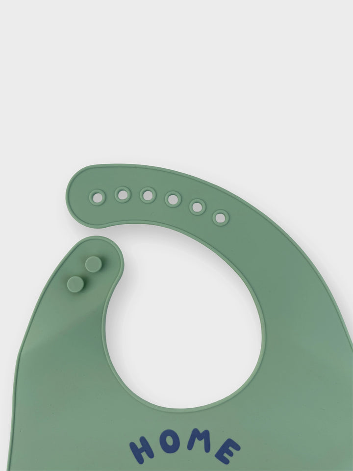 Green silicone bib with 'HOME' text on a white background