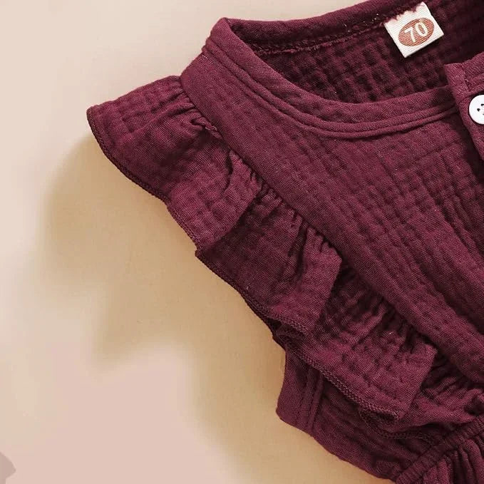 Maroon baby romper with ruffled details on a beige background