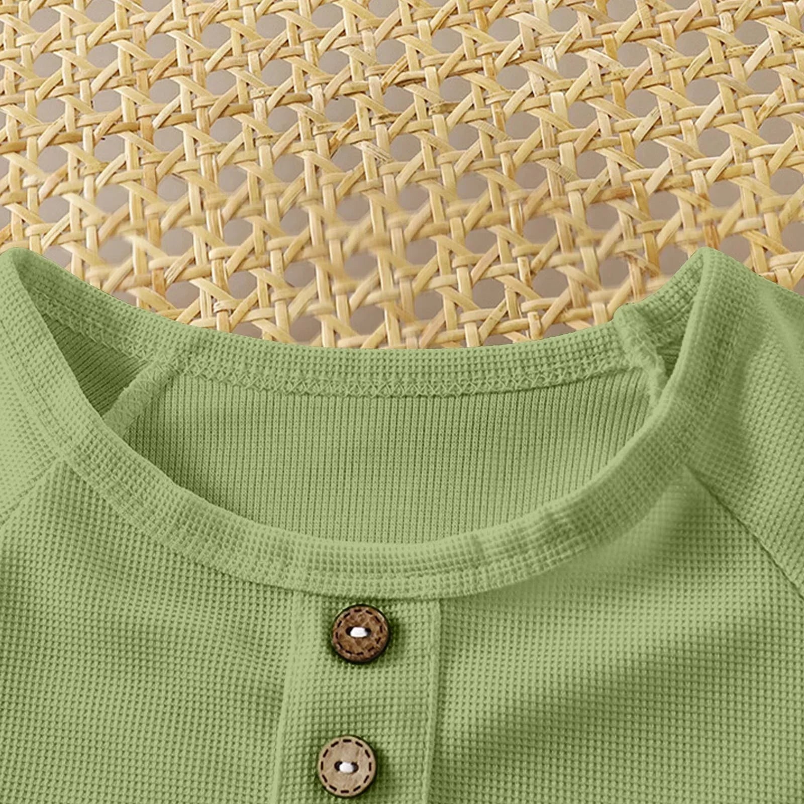 Close-up of a green garment with buttons against a woven mat background