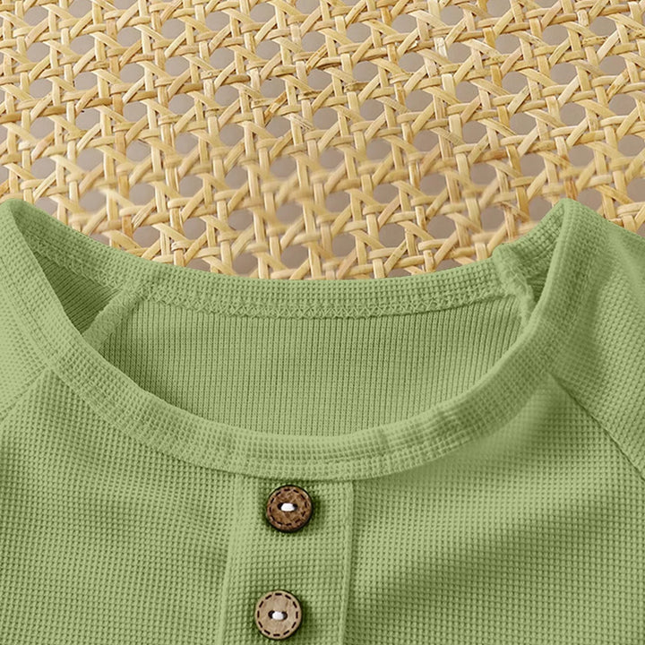 Close-up of a green garment with buttons against a woven mat background