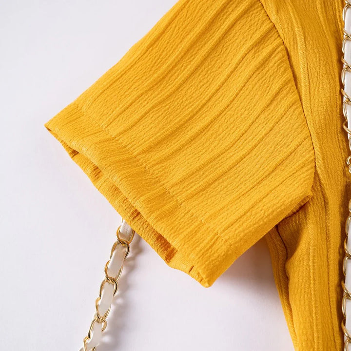 Yellow handbag with a chain strap on a white background
