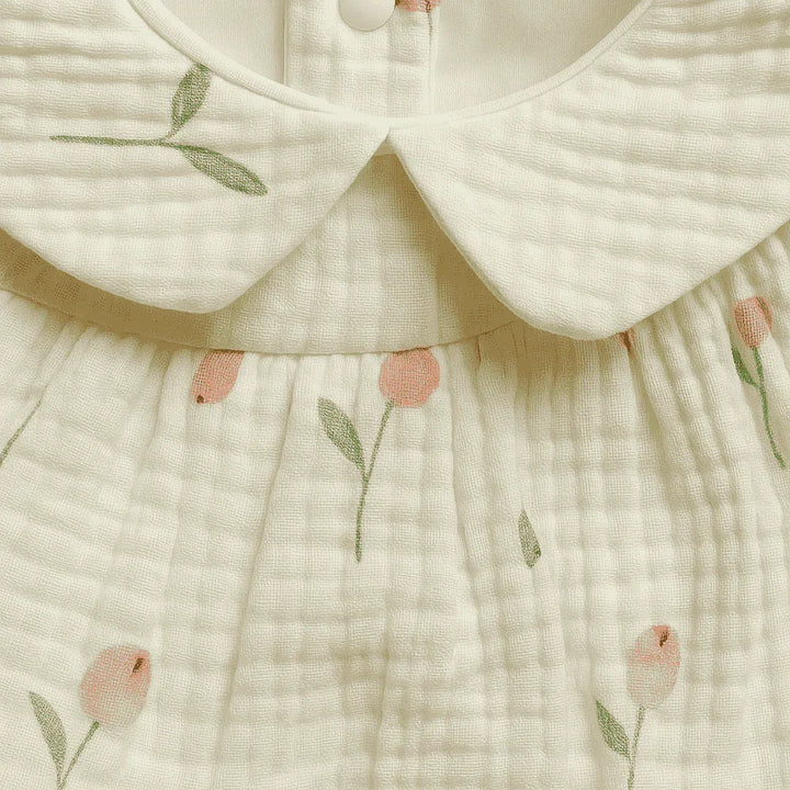 Close-up of a baby dress with floral embroidery on a light background