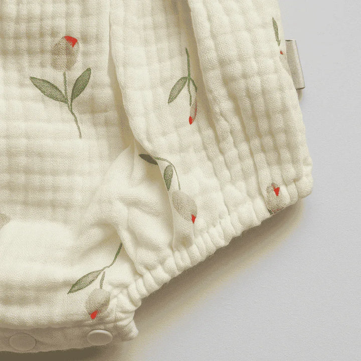 Close-up of a baby outfit with floral embroidery on a light background