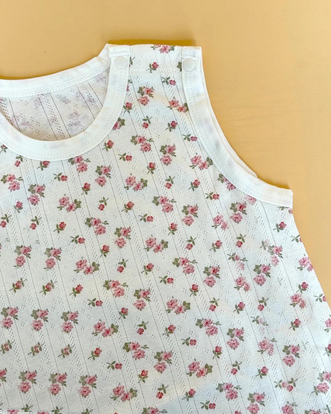White sleeveless top with pink floral pattern on a beige background