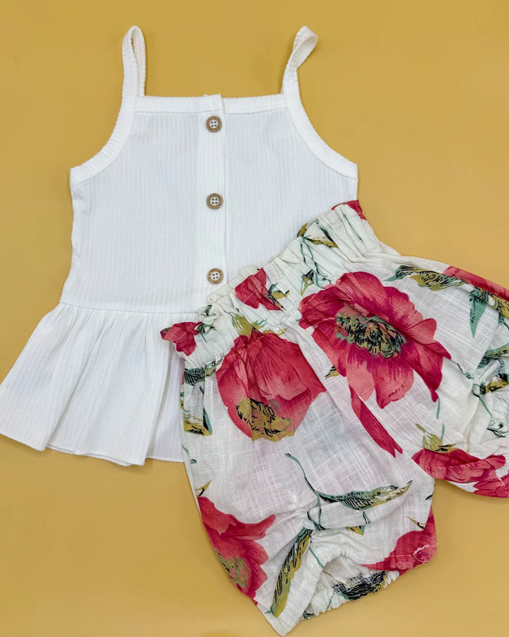 White sleeveless top with floral shorts on a yellow background