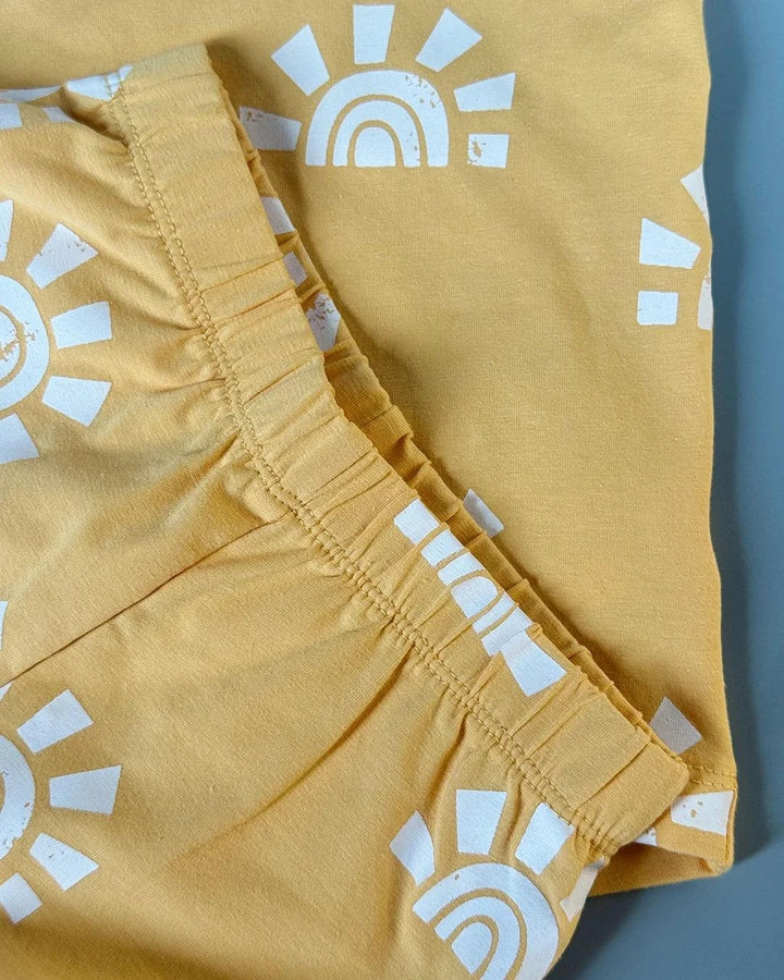 Yellow shorts with white sun and rainbow pattern on a blue background