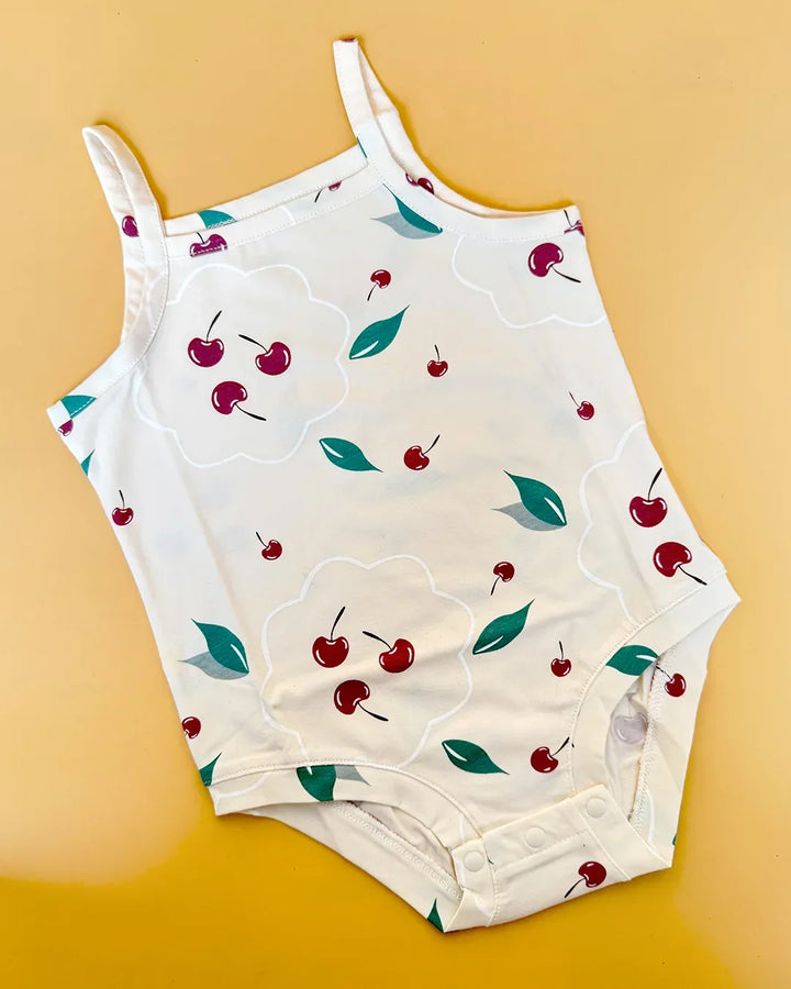 White children's romper with cherry pattern on a yellow background