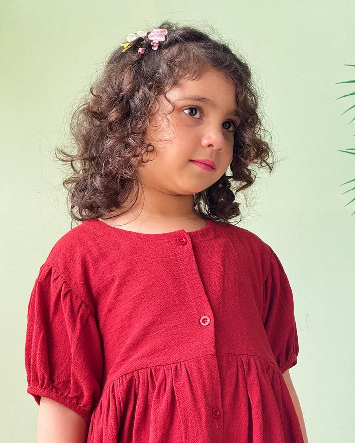 Young girl wearing a red dress against a light green background