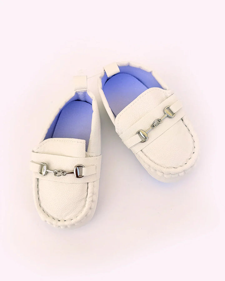 White loafers with decorative buckles on a light background