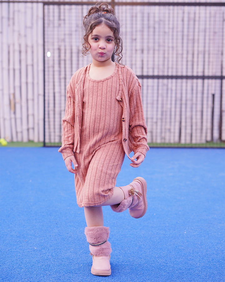 Young girl in pink outfit standing on a blue surface