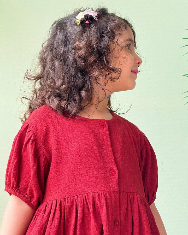Young girl wearing a red dress against a light green background