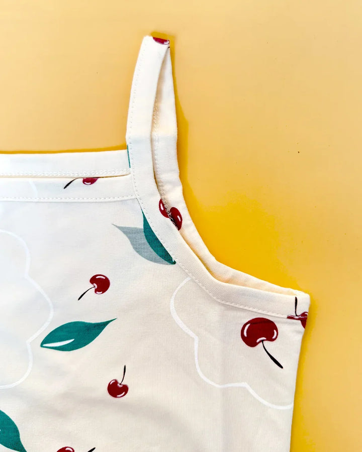 White apron with red cherry and green leaf pattern on a yellow background